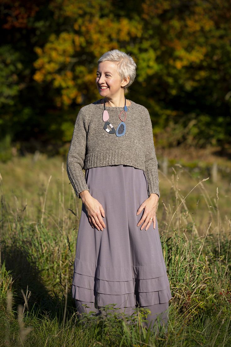 an older woman standing in tall grass with her hands on her hips