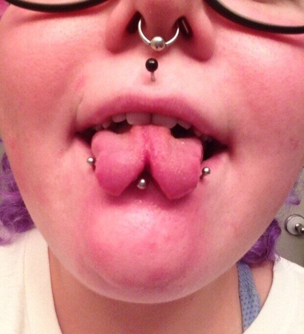 a close up of a person wearing glasses and piercings on their nose with a fake tongue