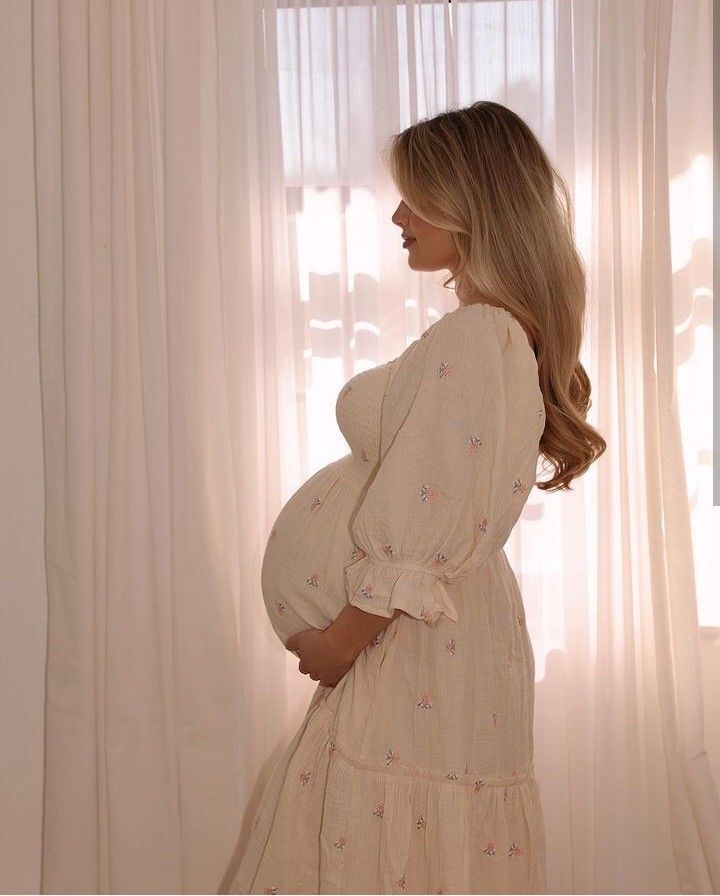 a pregnant woman standing in front of a window