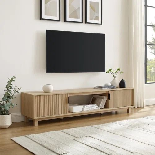 a living room with a large flat screen tv mounted on the wall and two framed pictures above it