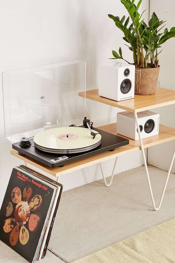 a record player sitting on top of a wooden table next to a potted plant