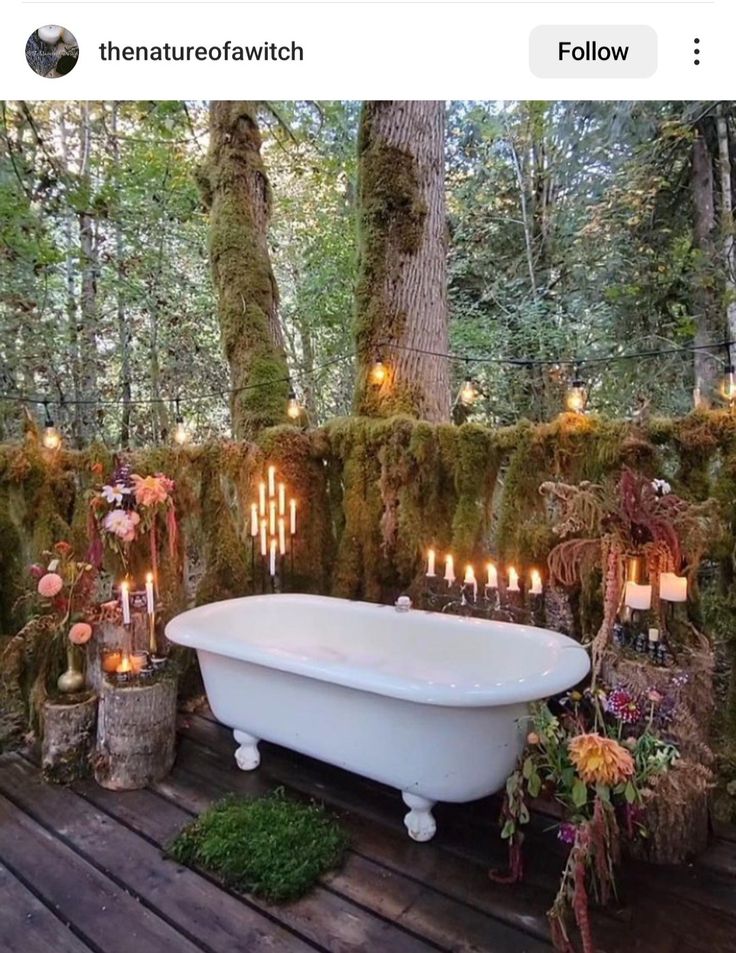 a bathtub in the middle of a wooden deck with candles and moss growing on it