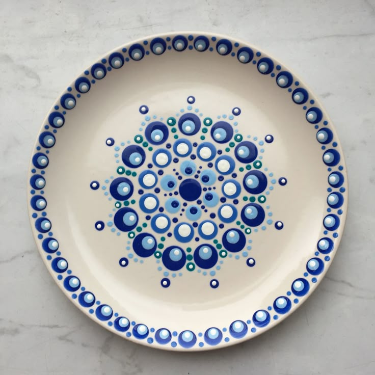 a blue and white plate with circles on it sitting on a marble counter top next to a tile wall