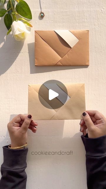 two hands are holding an envelope with the word cookie and craft on it next to some flowers