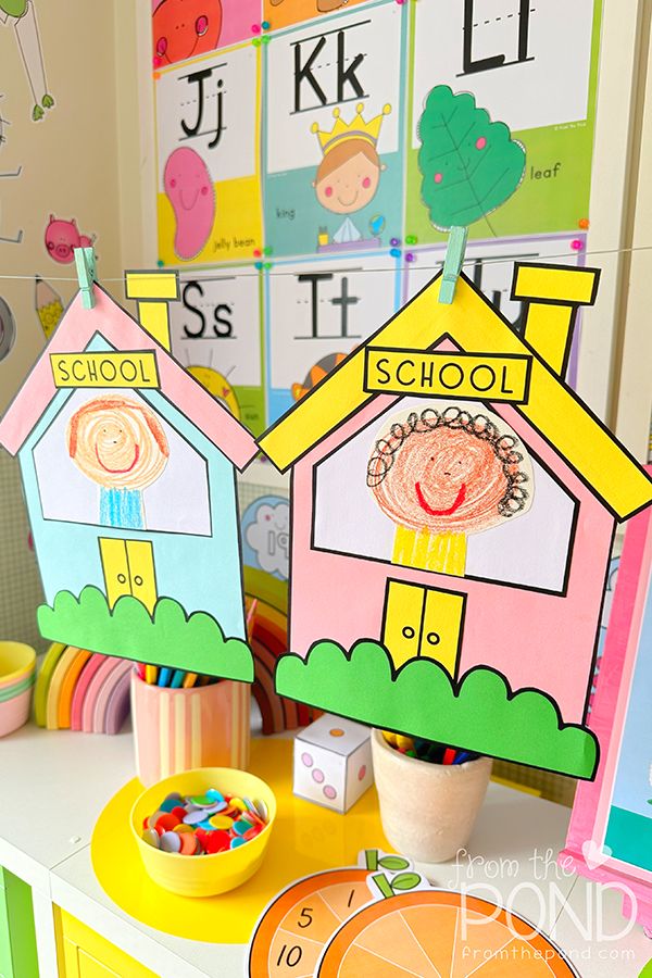 two paper houses on top of a table next to a clock and other items in front of them