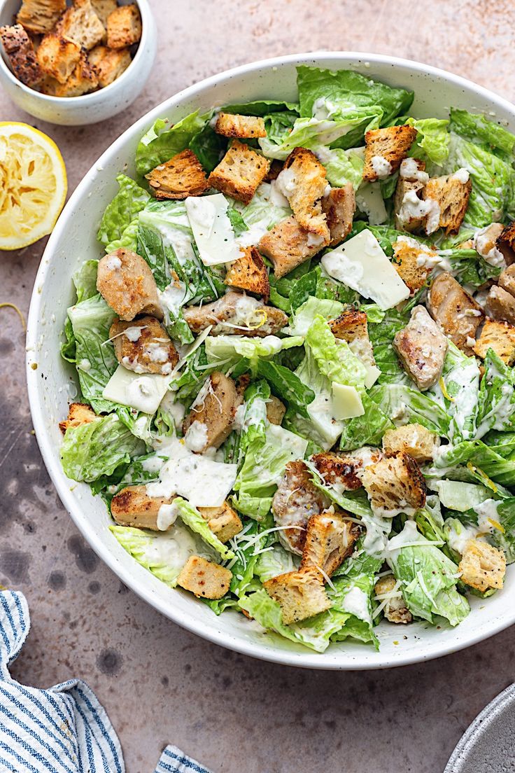 a white bowl filled with salad next to lemon wedges