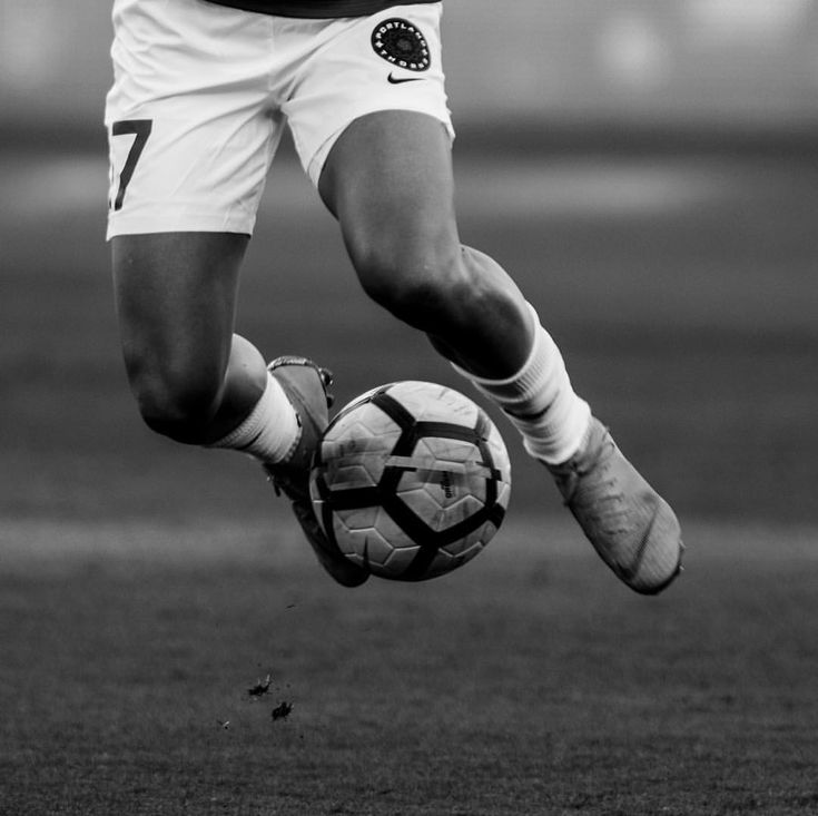 a man kicking a soccer ball on top of a field