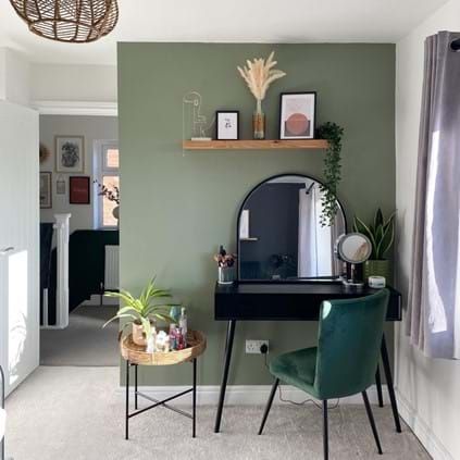 a room with a desk, mirror and plants on the shelf in it's corner