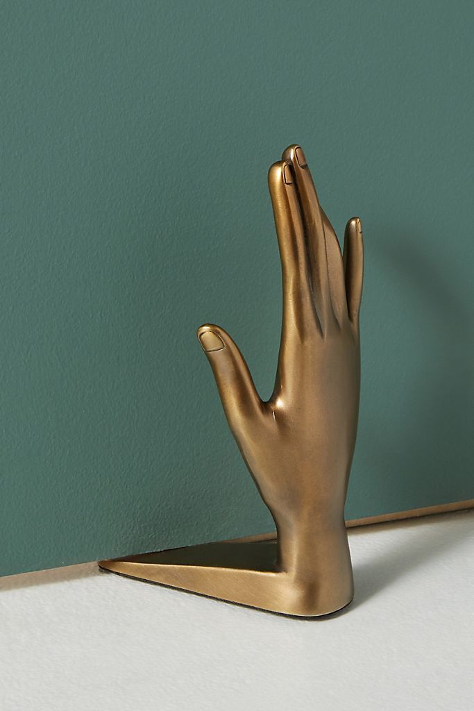 a gold hand statue on a white countertop next to a green wall and a blue wall