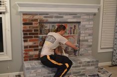 a woman painting a brick fireplace in her living room