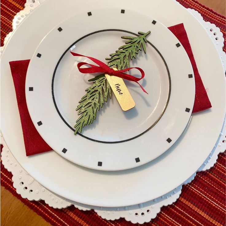 a white plate topped with a red ribbon next to a christmas tree ornament