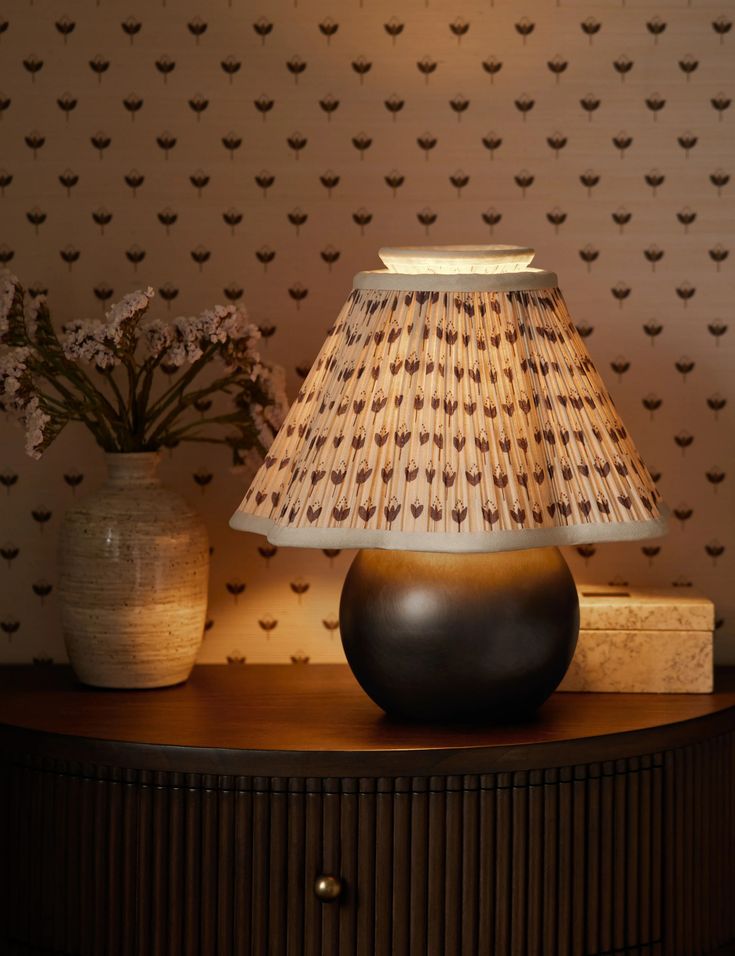 a lamp sitting on top of a table next to a vase with flowers in it