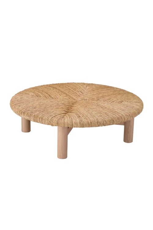 a wicker coffee table with wooden legs and an oval design on the top, against a white background