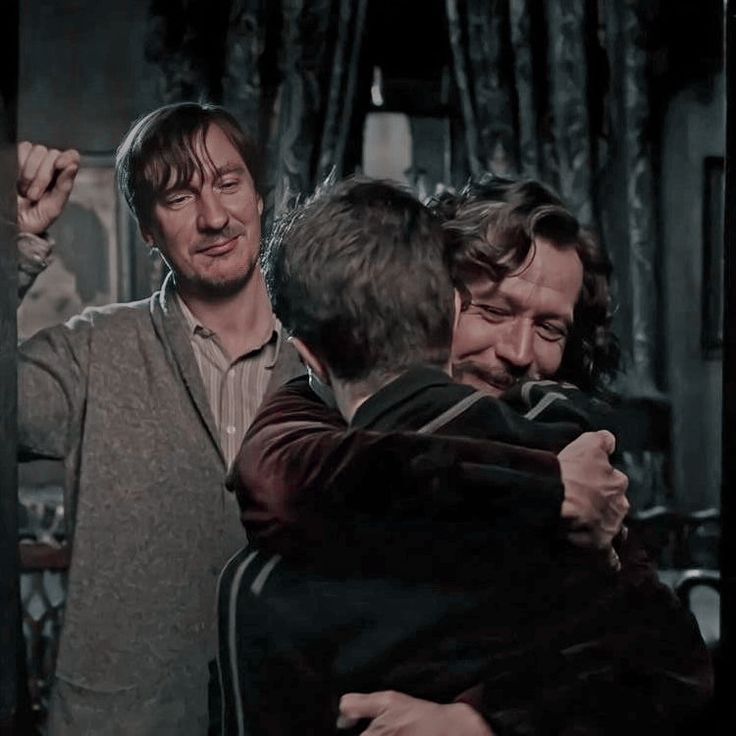 two men hug each other in front of a mirror while another man looks at them