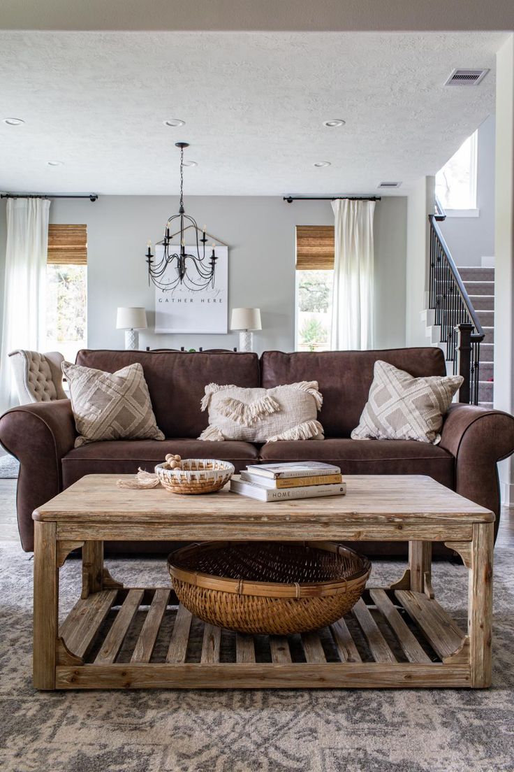 a living room with couches, coffee table and chandelier in the background