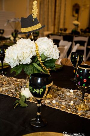 a black table cloth with white flowers and gold trimmings is topped by a centerpiece