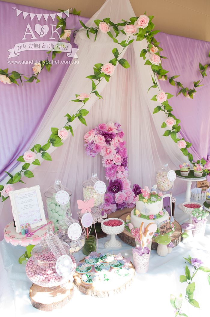 a table topped with lots of cakes and desserts next to a white tent covered in flowers