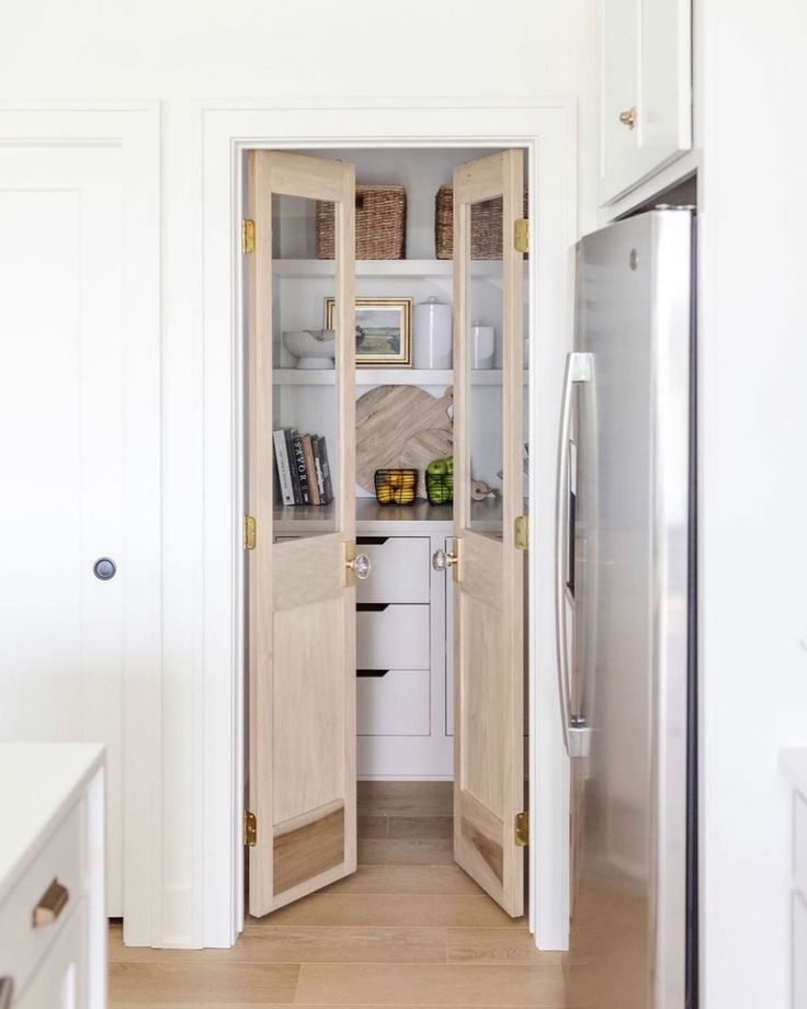 an open door leading into a kitchen with white cabinets and wood flooring on the walls