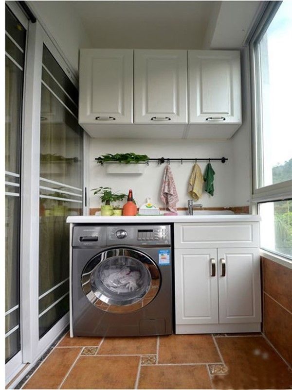 a washer and dryer in a small room with white cupboards on the wall