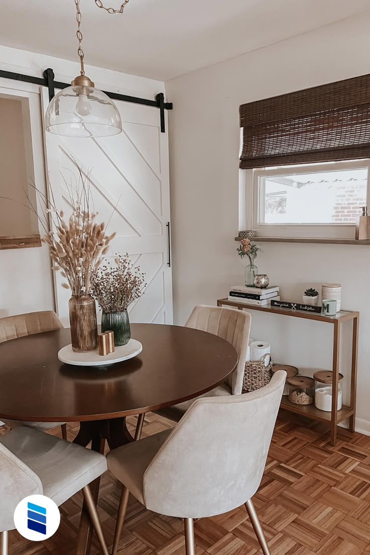 a dining room table with four chairs and a vase on top of it in front of a window