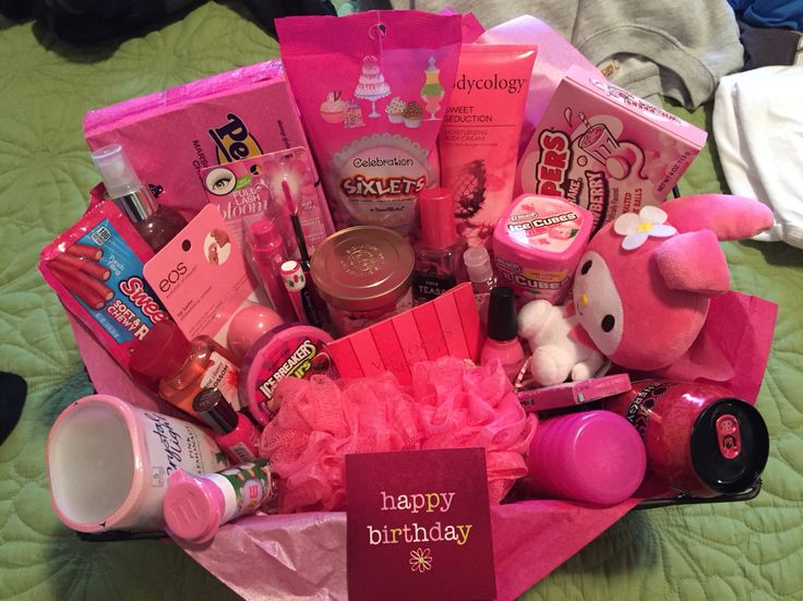 a pink birthday gift basket on a bed