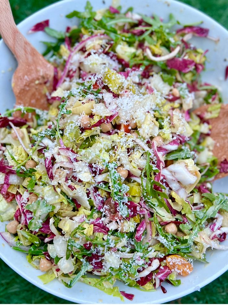 a salad with lettuce, radishes, and other vegetables in a white bowl