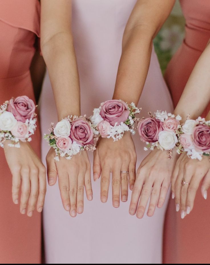 four bridesmaids in pink dresses hold their hands together with flowers on them,