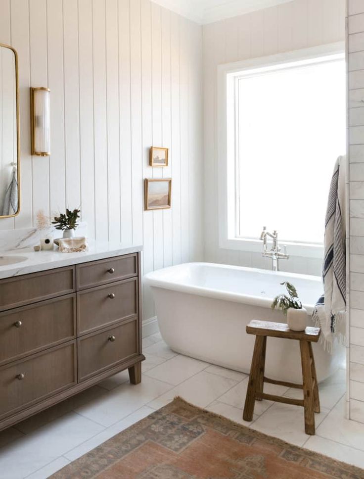 a bathroom with a tub, mirror and stool in the corner on the floor next to the bathtub