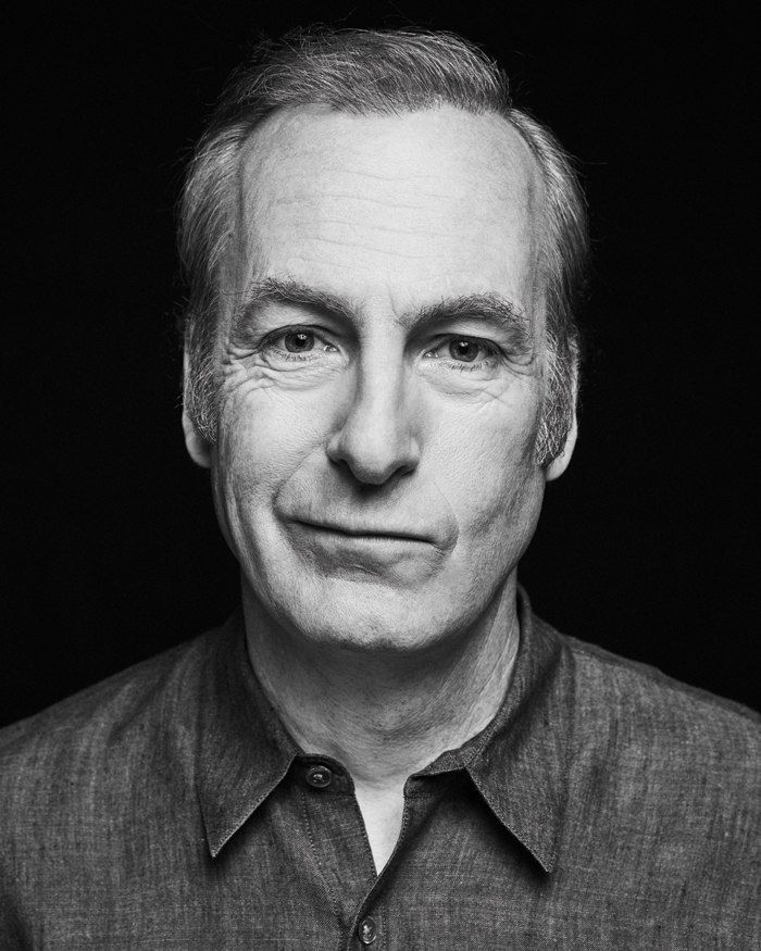 a black and white photo of a man in a button up shirt looking at the camera