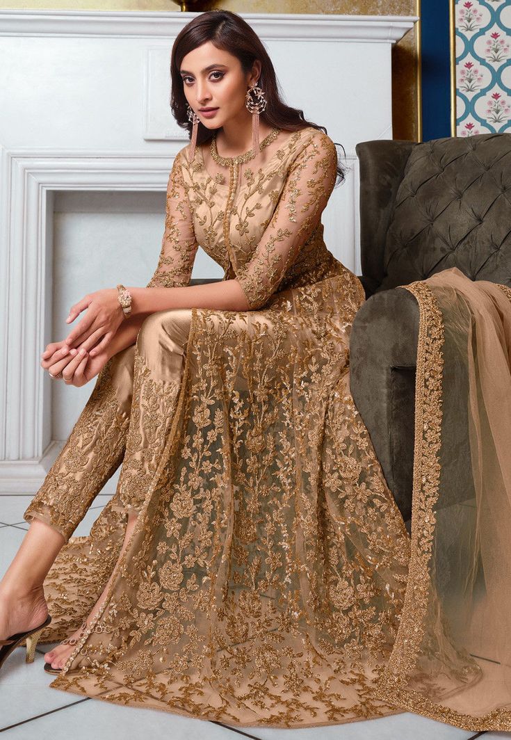 Net Abaya Style Front Slitted Kameez in Beige This Semi-stitched Attire with Satin Lining is Enhanced with Dori, Zari and Sequins Work. Crafted in Round Neck and Quarter Sleeves Available with a Satin Pant in Beige and a Net Dupatta in Beige The Kameez and Bottom Lengths are 52 and 38 inches respectively Do note: Accessories shown in the image are for presentation purpose only and length may vary upto 2 inches.(Slight variation in actual color vs. image is possible). Anarkali Palazzo Set With Gold Embroidery For Eid, Traditional Long Sleeve Palazzo Set With Gold Embroidery, Festive Long Sleeve Palazzo Set With Gold Embroidery, Gold Long Sleeve Gown With Zari Work, Gold Palazzo Set With Resham Embroidery, Floor-length, Gold Zari Work Long Sleeve Gown, Gold Resham Embroidered Floor-length Palazzo Set, Gold Resham Embroidery Floor-length Palazzo Set, Semi Formal Vs Formal