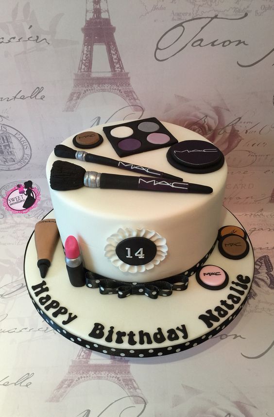 a birthday cake with makeup and eye shadows on the top tier, in front of a paris eiffel tower backdrop