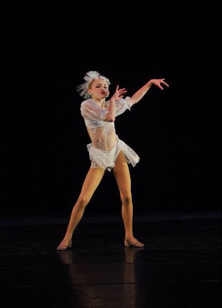 a woman in white is dancing on stage