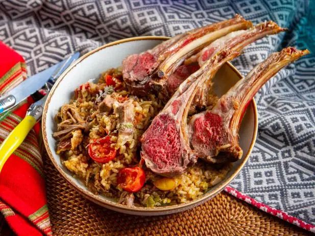 a bowl filled with meat and rice on top of a table next to a fork