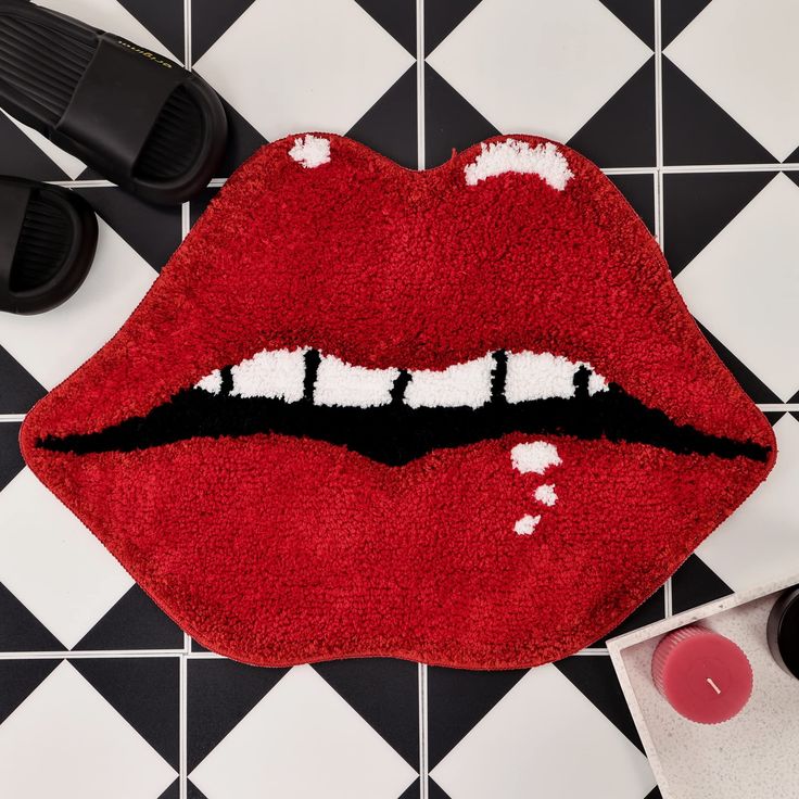 a red rug with the shape of a mouth painted on it next to black and white checkered flooring