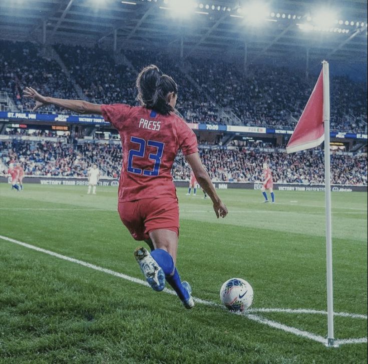 a woman kicking a soccer ball on top of a field