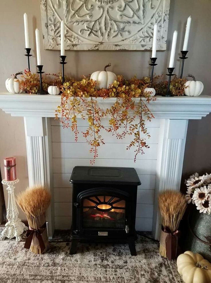 a fireplace with candles, pumpkins and other decorations on top of the mantel