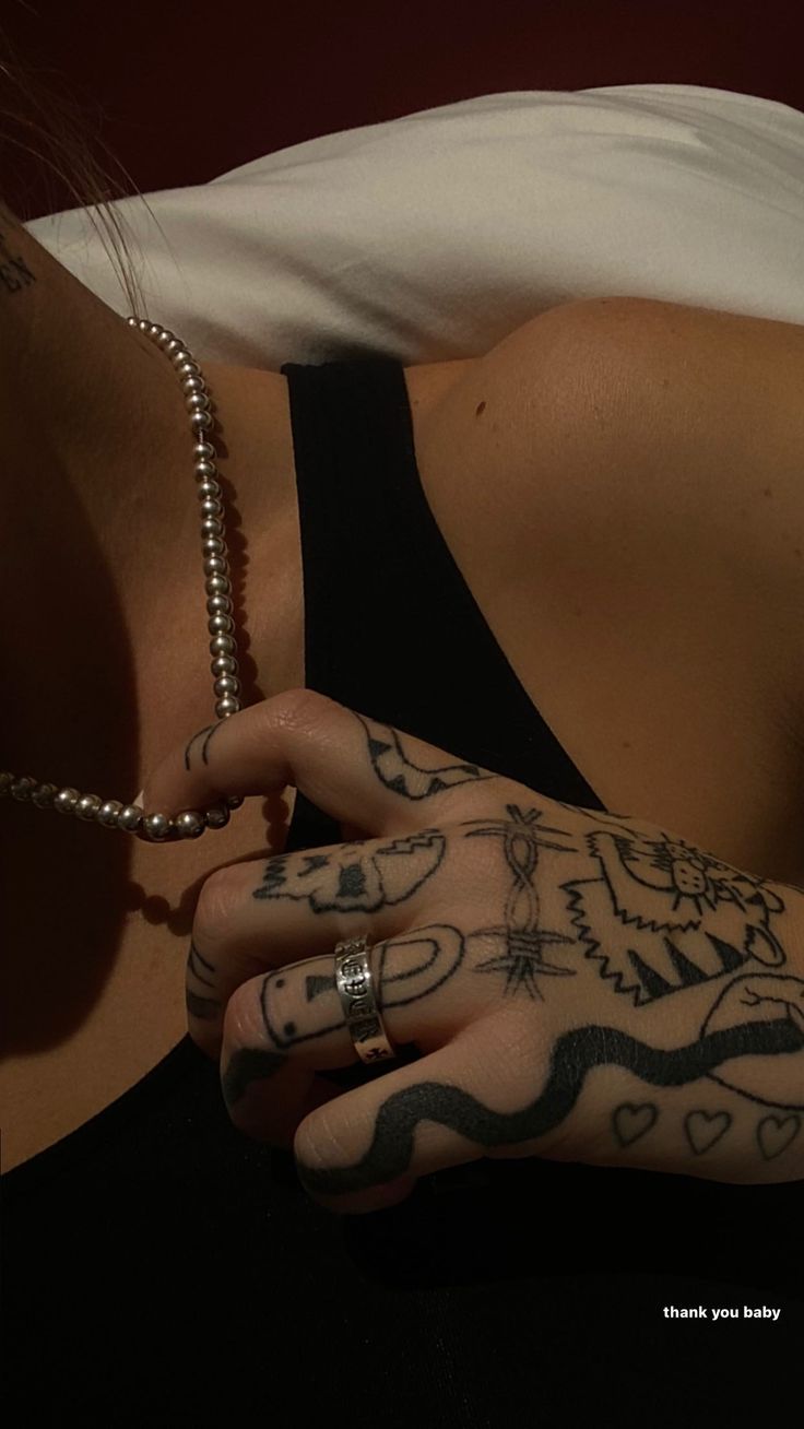 a woman with tattoos on her arm and hand holding a ball chain in front of her face