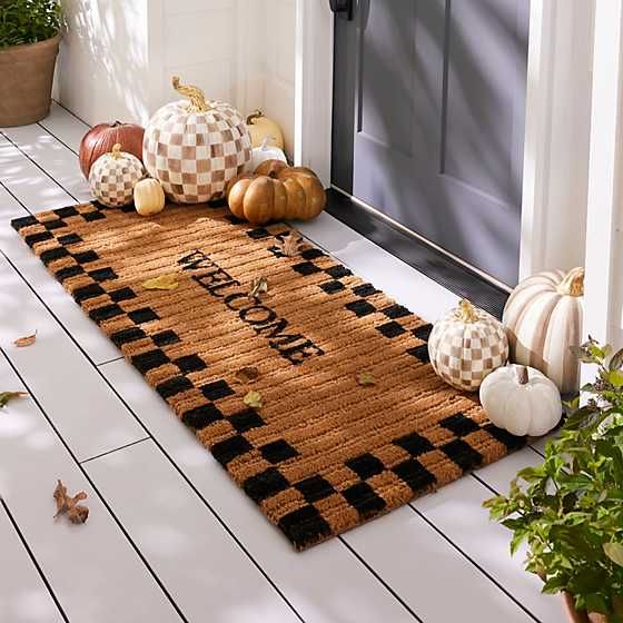 a welcome mat with pumpkins and gourds on the front porch