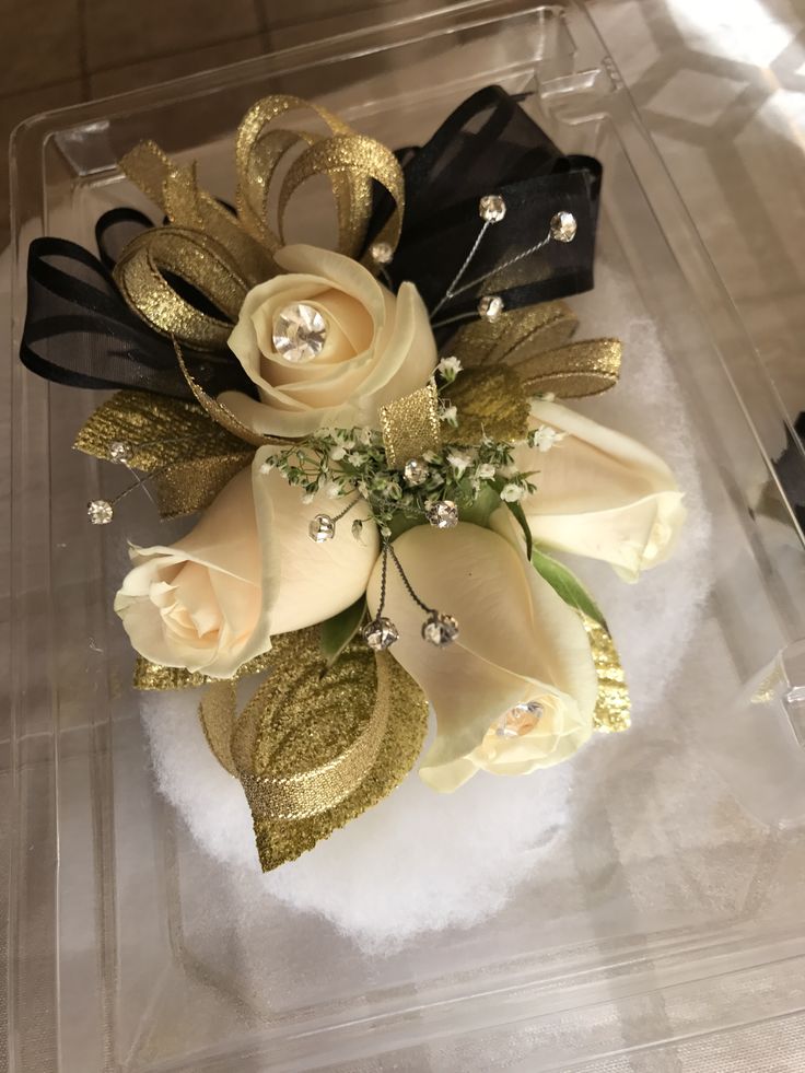 a white rose and black ribbon corsage in a clear plastic container on a table