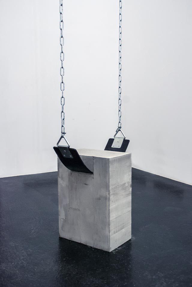 a concrete block with chains hanging from it's sides and two black square objects in the middle