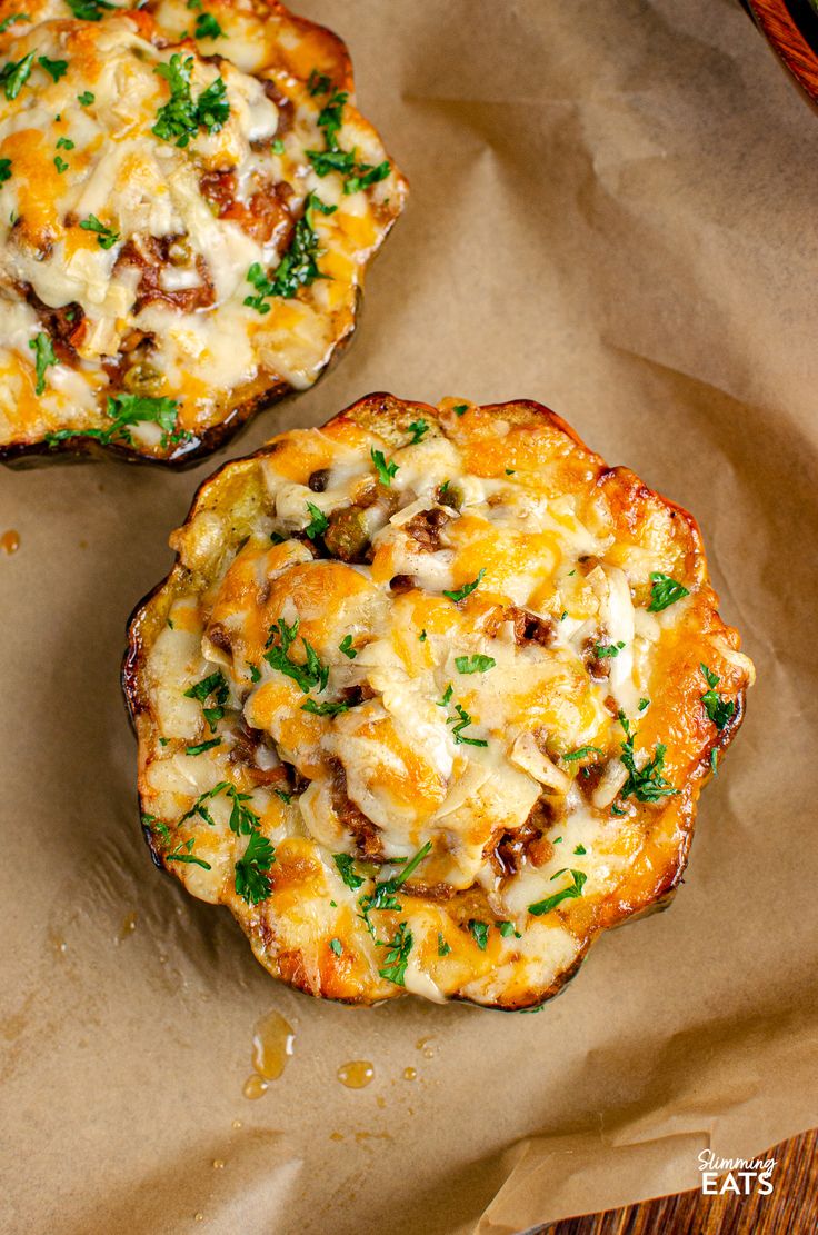 two mini pizzas sitting on top of a piece of wax paper covered in cheese