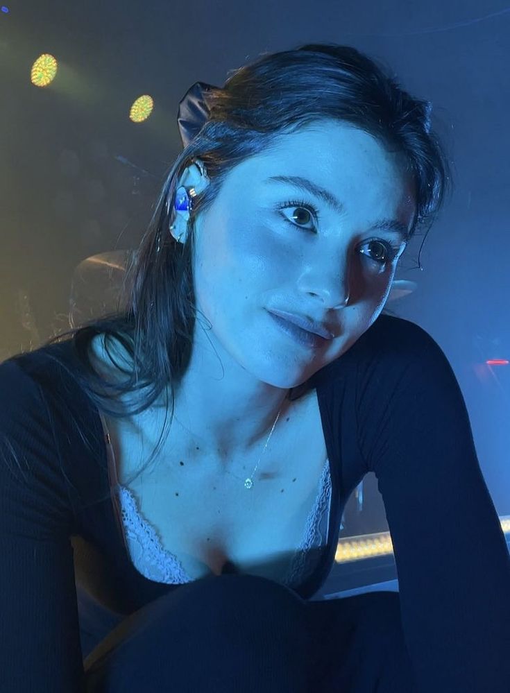 a woman is posing for the camera in front of some lights