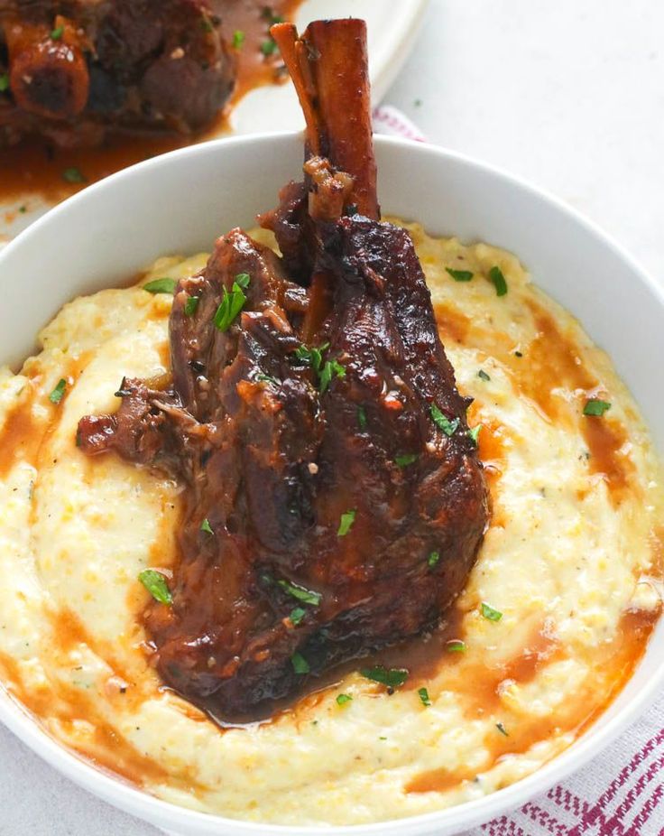 a white bowl filled with mashed potatoes and meat on top of it's side