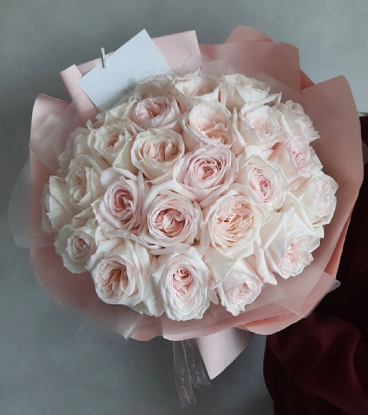 a bouquet of white and pink roses with a card attached to the top of it