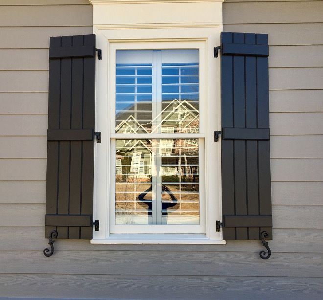 an open window with shutters on the side of a house in front of it