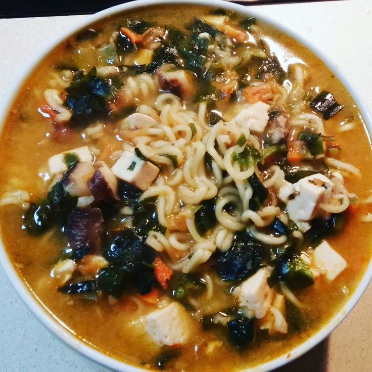 a bowl of soup with noodles, meat and vegetables in it sitting on a table