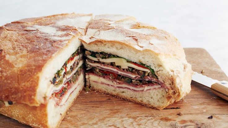 a cut in half sandwich sitting on top of a cutting board next to a knife