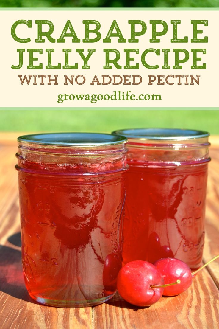 two jars filled with cranberry jelly sitting on top of a wooden table next to cherries