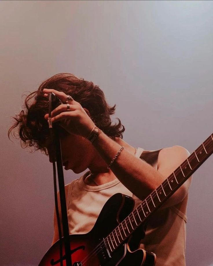 a man holding a guitar while standing next to a microphone