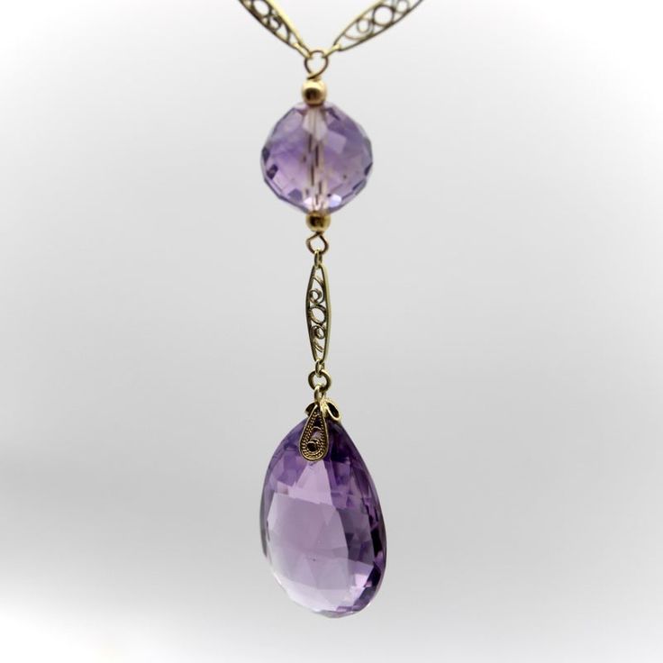 This is part of Chairish’s Fine Jewelry assortment.  The hand faceted Rose de France amethyst beads in this 14k gold Edwardian necklace have stunning facets that catch the light like prisms. The center stone is a flattened teardrop-shaped briolette with elongated triangular facets. The round beads along the chain descend in size; each are hand faceted and subtly different in shape, like tulip bulbs. The stones are the pale purple that Rose de France is known for—a lighter colored amethyst with softer tones that are romantic and feminine. The amethyst beads are sandwiched between 14k gold wirework, held together by traditional French fancy links—narrow almond shaped links with intricate filigree work. Circa 1915, the lace like quality of this necklace is very elegant but also suggests a mov Exquisite Amethyst Necklace For Formal Occasions, Exquisite Formal Amethyst Necklace, Purple Teardrop Fine Jewelry Necklace, Formal Fine Jewelry Amethyst Necklaces, Formal Fine Jewelry Amethyst Necklace, Formal Amethyst Necklace In Fine Jewelry Style, Purple Drop Necklace For Formal Occasions, Elegant Purple Teardrop Gemstone, Formal Purple Drop Necklace